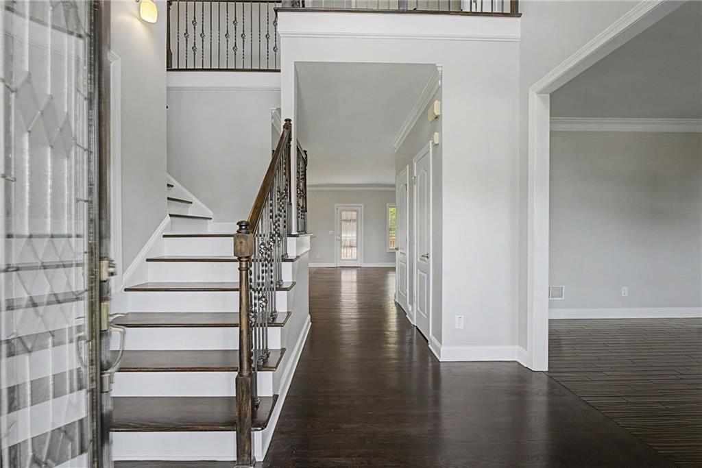 Two-story foyer with hardwood stairs and wrought-iron balusters