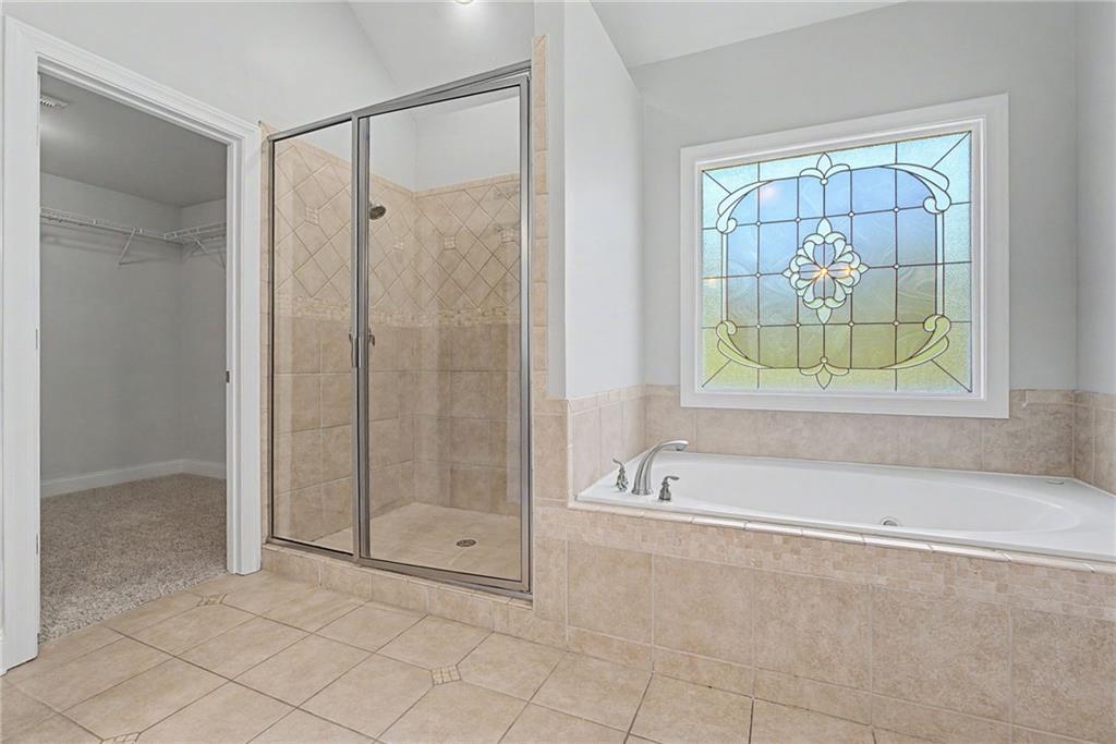 Primary bathroom with soaking tub, tiled shower and stained-glass window